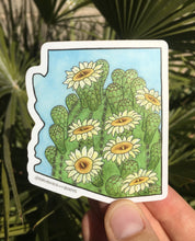 Load image into Gallery viewer, Vinyl sticker in the shape of Arizona with a watercolor painting of the top of a saguaro cactus with white blooming flowers.