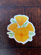 Load image into Gallery viewer, A sticker with a watercolor illustration of orange poppy flowers on a dark wood table
