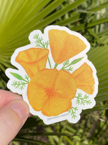 Hand holding a sticker of a watercolor illustration of an orange poppy wildflower