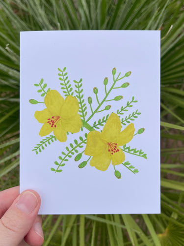 Hand holding a card with a watercolor illustration of yellow palo verde flowers against a green leafy background